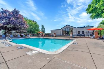 A large outdoor swimming pool surrounded by a concrete patio and trees.